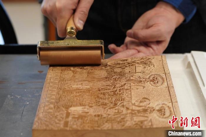 圖為徐晉林工作室工作人員正在給雕好壁畫的版面滾油墨?！【琶赖┰?　攝