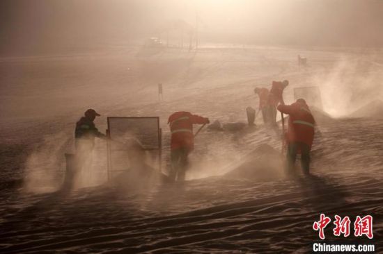 圖為敦煌市鳴沙山月牙泉景區(qū)“駱駝保姆”清理駱駝糞便?！垥粤?攝