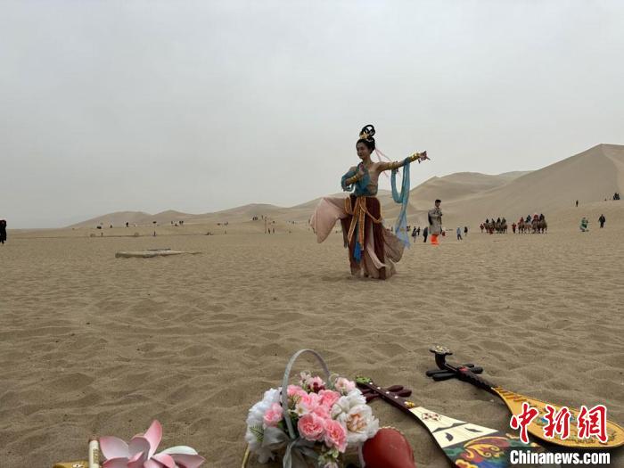 圖為2023年4月底，敦煌大漠“逐舞者”奧楠在鳴沙山月牙泉景區(qū)視頻直播敦煌舞?！●T志軍 攝