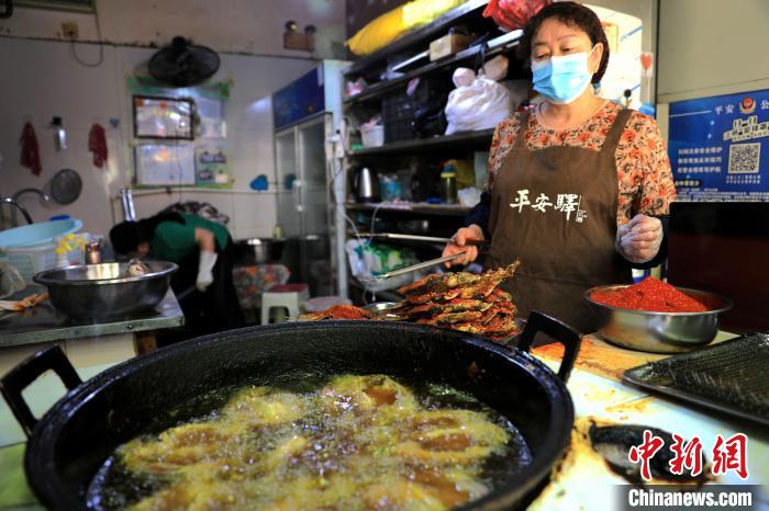 圖為平安驛·河湟民俗文化體驗(yàn)地內(nèi)的商戶炸干板魚?！⊙Φ?攝