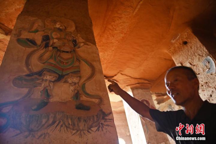7月15日，甘肅省平?jīng)鍪袥艽h百里石窟長廊羅漢洞石窟內，該窟文保員郭建平介紹窟內石刻彩繪壁畫。郭建平家中三代人曾自發(fā)保護羅漢洞石窟。羅漢洞石窟遺存40余個窟龕，以北魏至清代風格為主。中新社記者 李亞龍 攝</p>
<p>